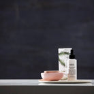 Salus Ultra Moisture Rose Facial Mist bottle on a tray with pink ceramic bowls against a dark wall
