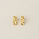 Pair of Bella gold earrings with a crushed, richly textured finish on a cream background