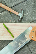 Olive green tooling pen on a sawn timber board with a hammer and a saw blade