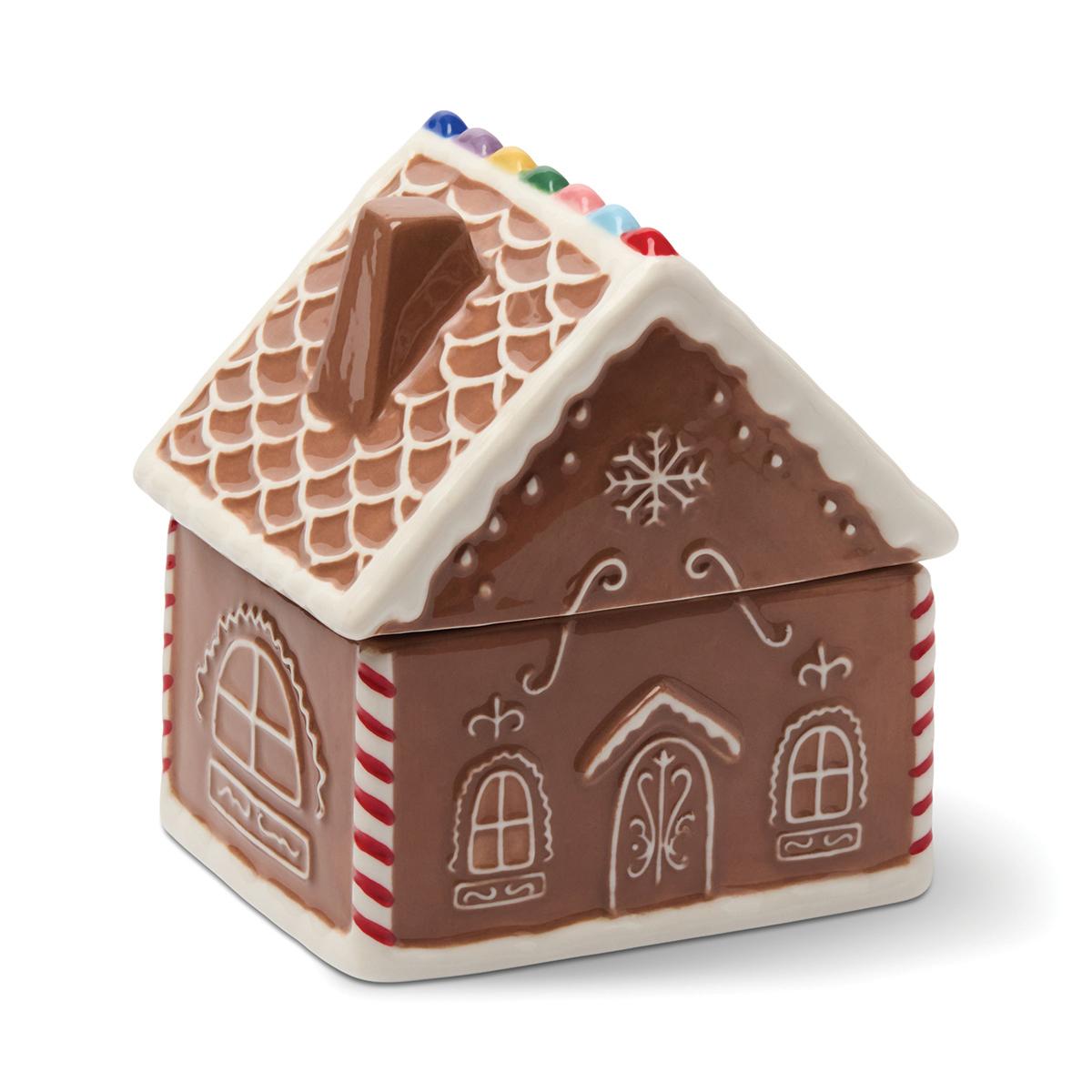 The gingerbread house from the front corner, with arched windows, a door and candy-striped corners.