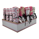 Angled view of the Geobloom display box of assorted rolled tea towels with swing tags