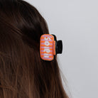 The beaded soleil claw clip worn in loose brown hair, seen from behind.