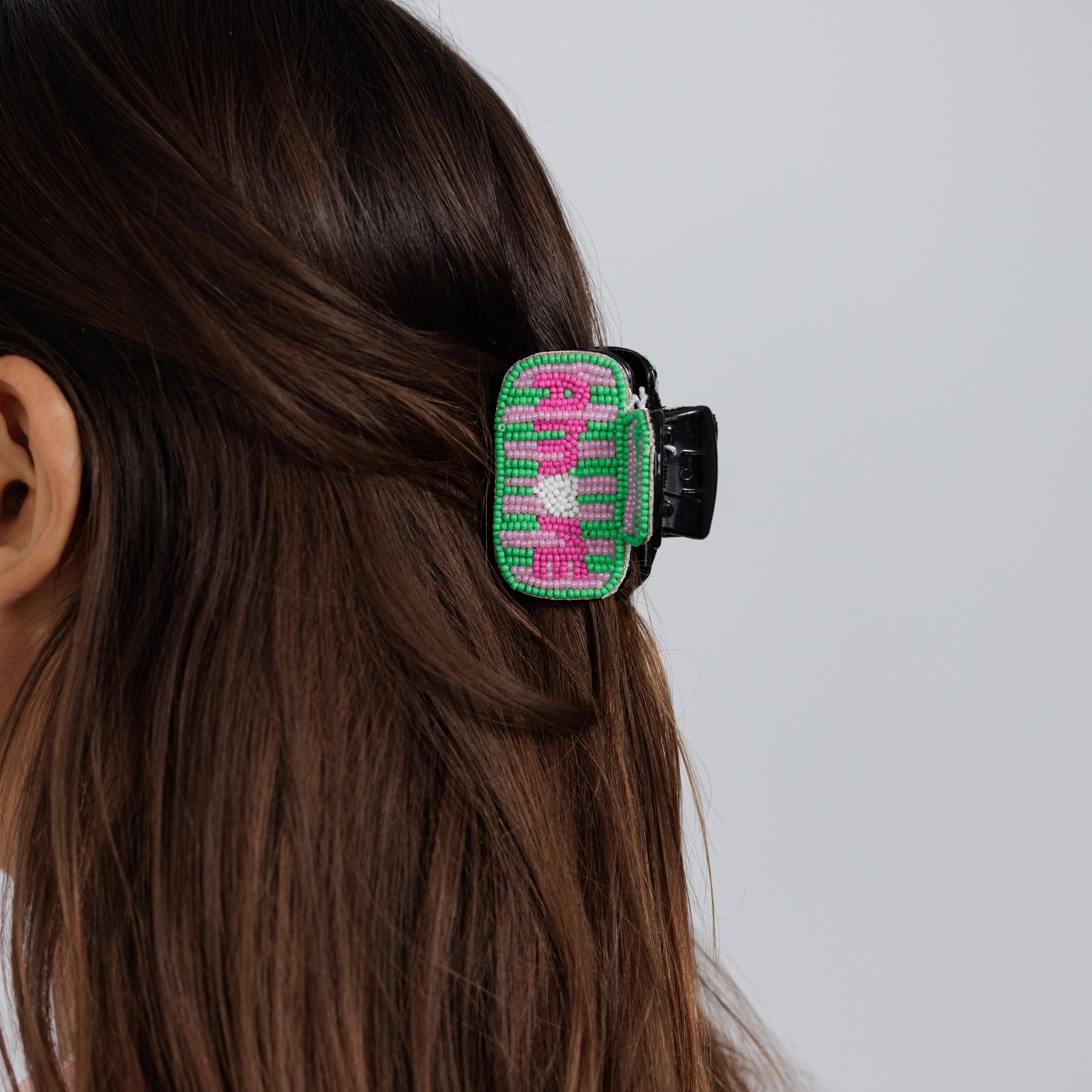 The beaded AMORE claw clip worn in loose brown hair, seen from behind.