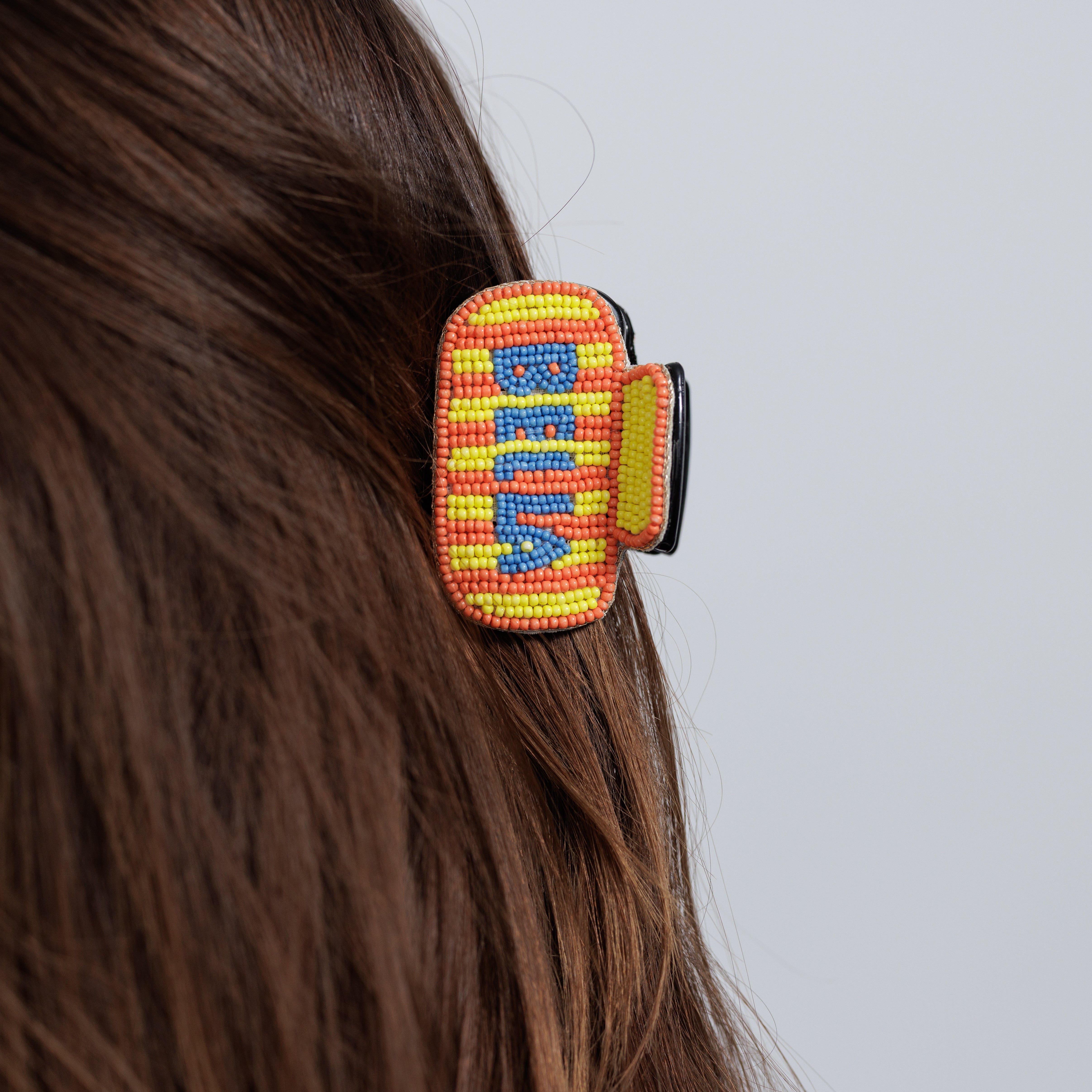 The beaded CIAO claw clip worn in loose brown hair, seen from behind.