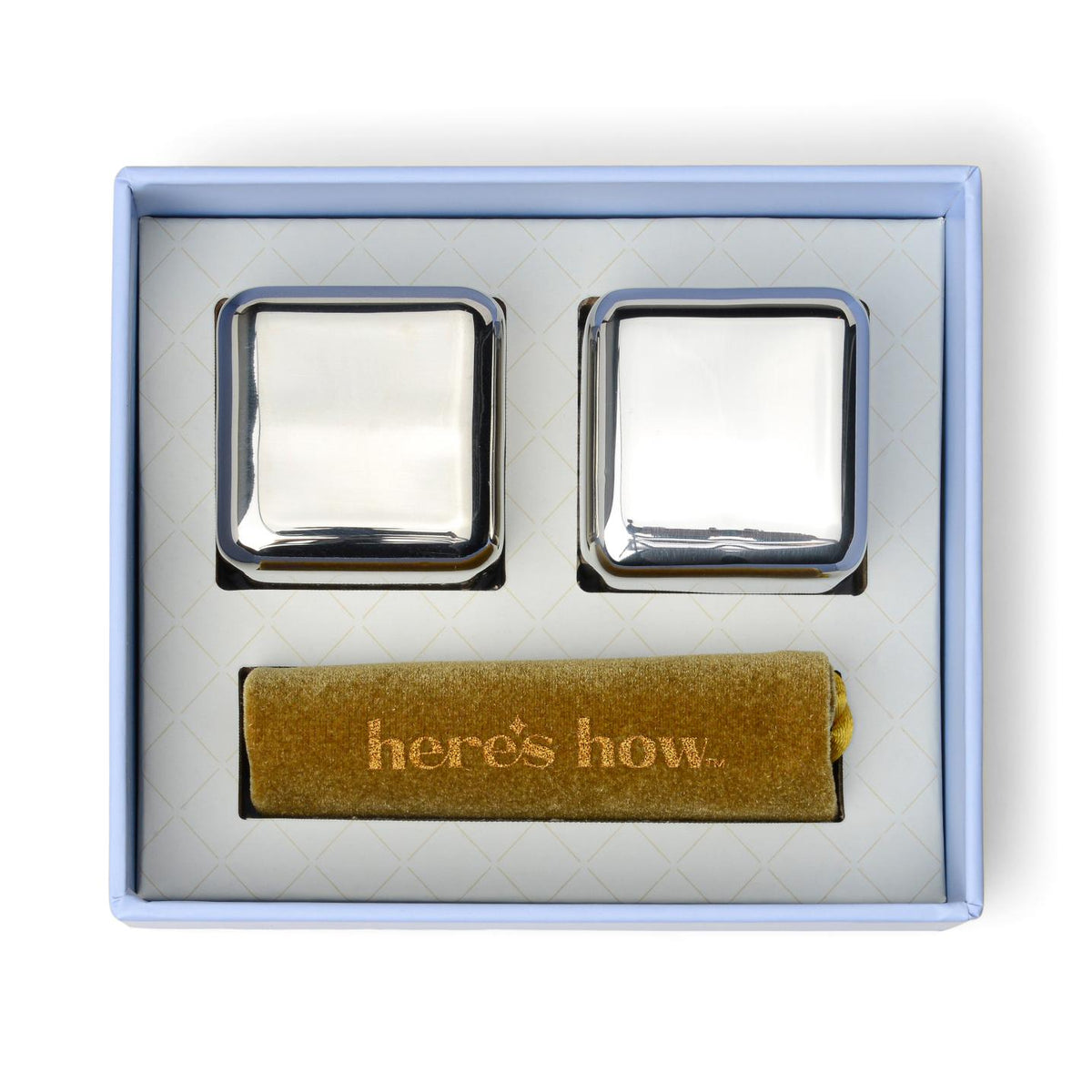 The pair of steel cubes and the gold Here's How pouch set into the open box
