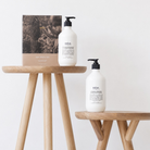 Salus Hand Rescue Duo box and hand wash on a timber stool, with the hand cream pump on a lower stool beside it
