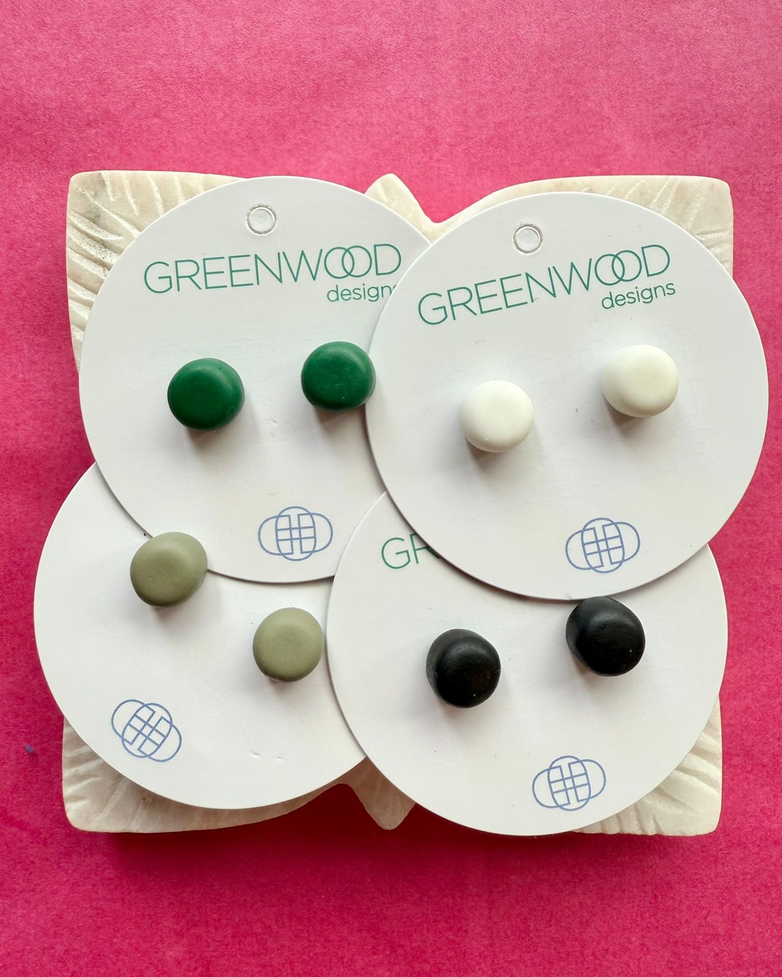 Round resin studs in Olive Green, White, Moss and Black on overlapping cards, on a carved white leaf dish.