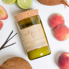 Coconut & Lime candle on white with peaches, coconut halves and vanilla pods