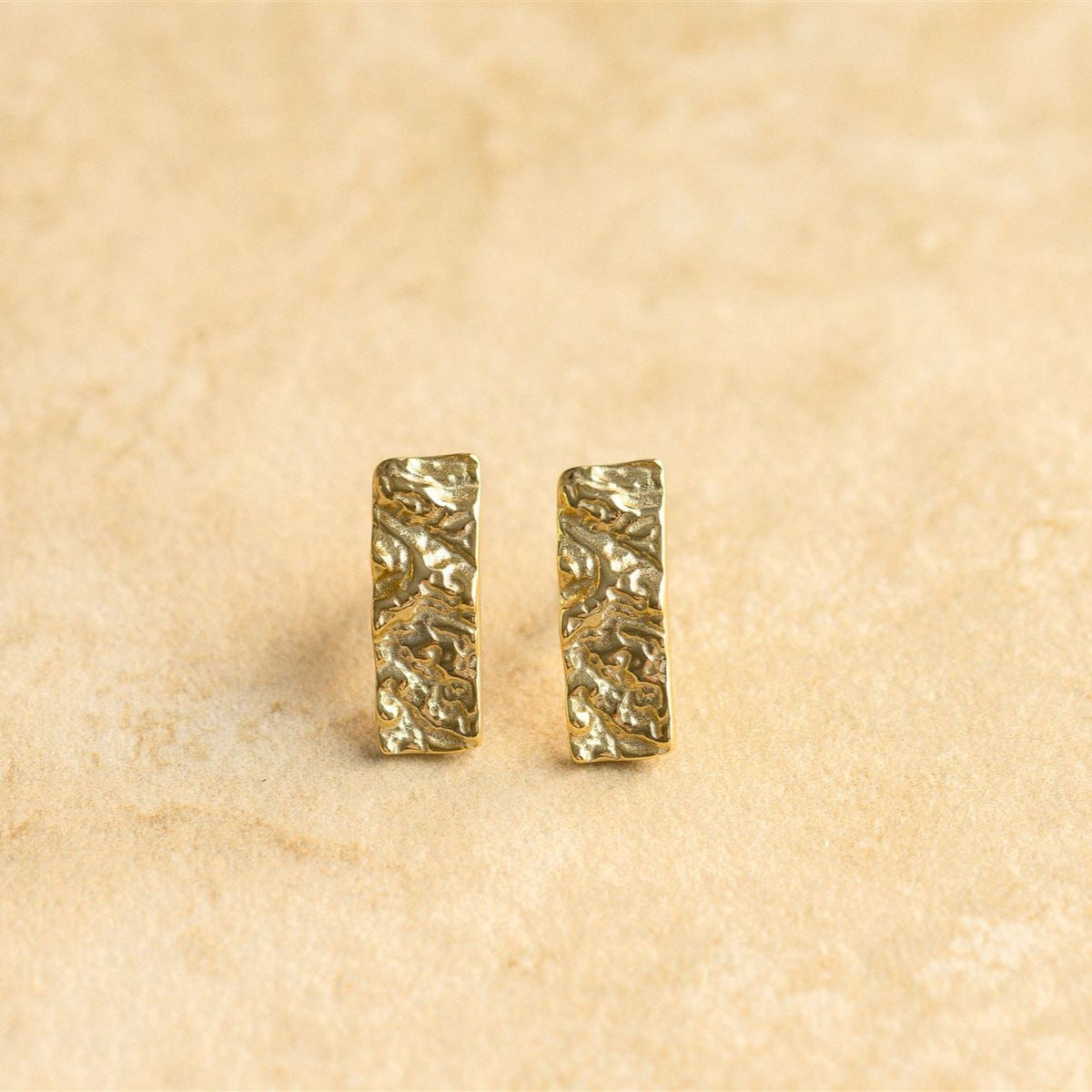 Bella gold earrings on a sandstone surface showing the hammered texture