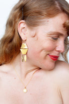Model with red hair wearing the gold geometric earring and a fine gold pendant necklace