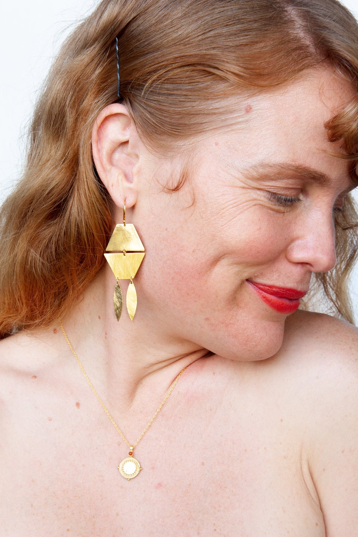 Model with red hair wearing the gold geometric earring and a fine gold pendant necklace