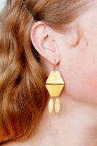 Close-up of the gold geometric drop earring worn with long red hair