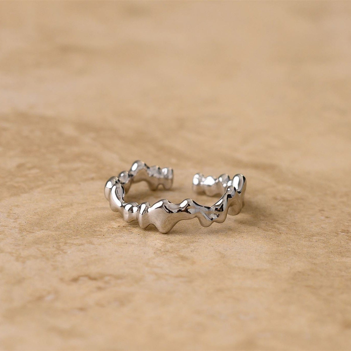 Alaia adjustable sterling silver ring with an organic textured band, on a sandstone surface