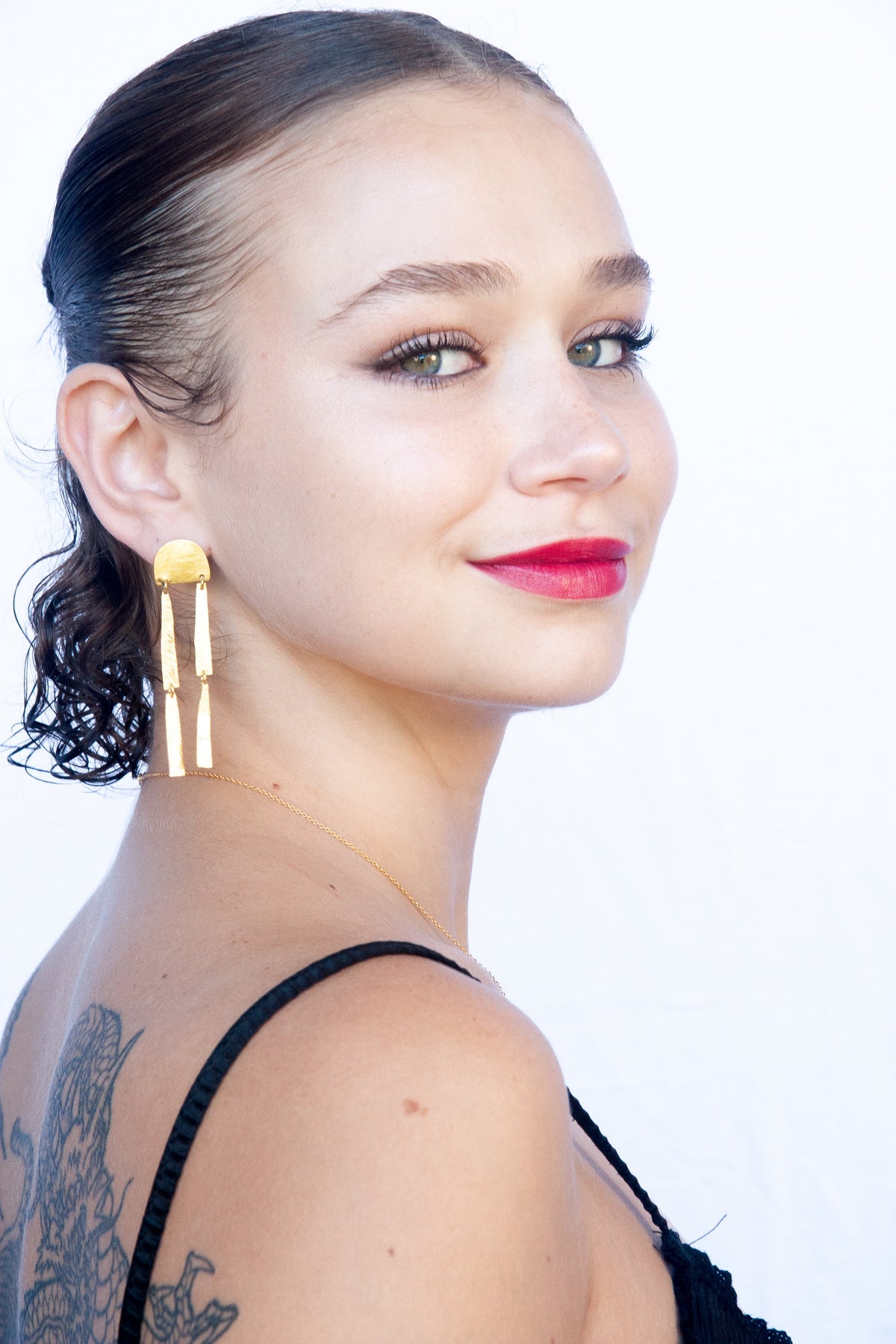 Smiling model with red lipstick wearing the gold arch bar-drop earring
