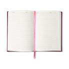 The journal open to its lined ivory pages, with the pink ribbon marker