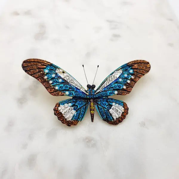 Crystal butterfly brooch in blue, brown and white on a marble surface