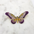 Crystal butterfly brooch in purple, pink and yellow on a marble surface