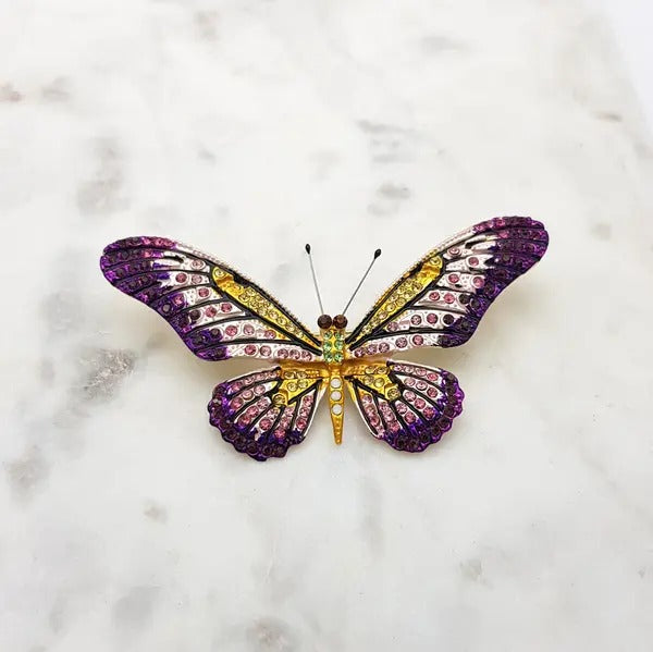 Crystal butterfly brooch in purple, pink and yellow on a marble surface