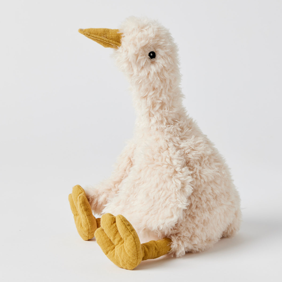 Shaggy cream plush duck sitting up in profile, with a long curved neck, a mustard beak and big mustard webbed feet