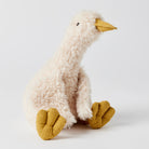 The cream duck facing the other way, small wings at its sides and both mustard feet stretched out in front