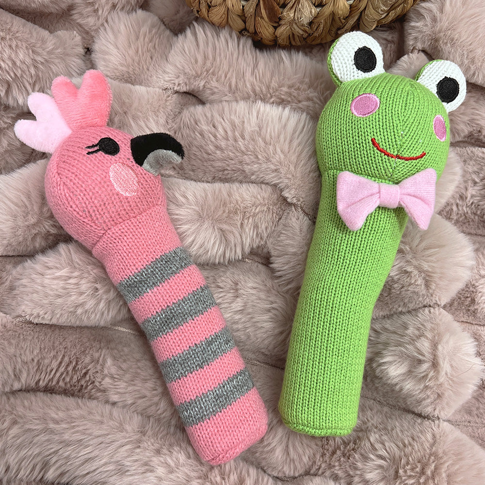 Galah and frog knit rattles lying on a fluffy pink blanket