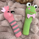 Galah and frog knit rattles lying on a fluffy pink blanket
