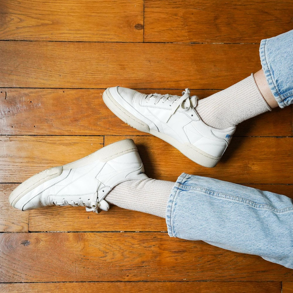 Pale shimmer KLUE lurex socks worn with white leather sneakers and rolled jeans on a timber floor