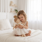 Little girl sitting on a bed hugging the Lottie doll