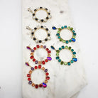 Assorted crystal circle drop earrings in red, green and black mixes on a marble tile