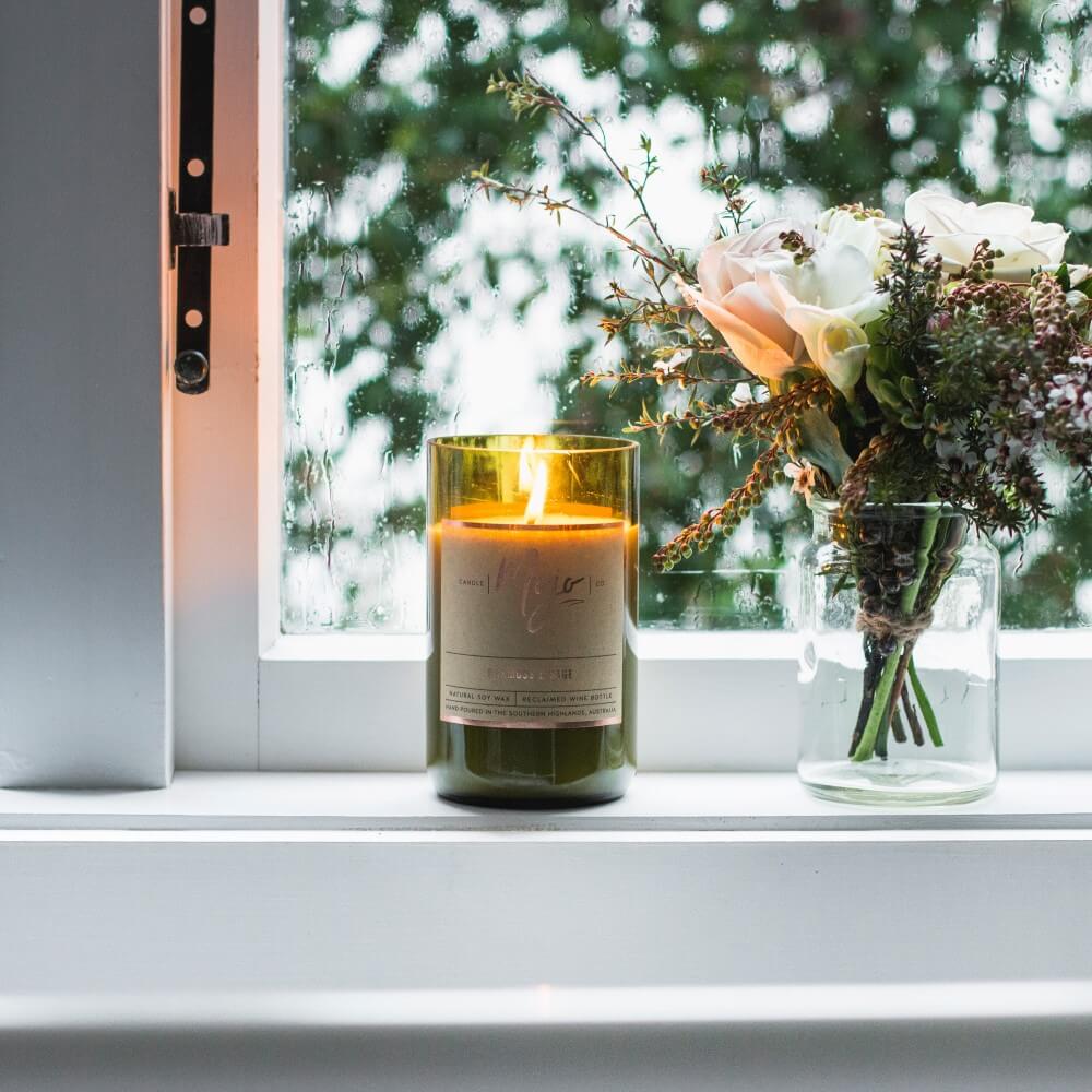 Lit Coconut & Lime candle on a windowsill beside a glass jar of dried flowers
