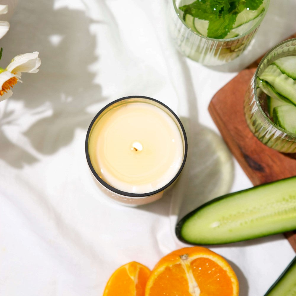 Top view of the open Cucumber & Muddled Mint candle showing its natural soy wax, with cucumber ribbons and orange
