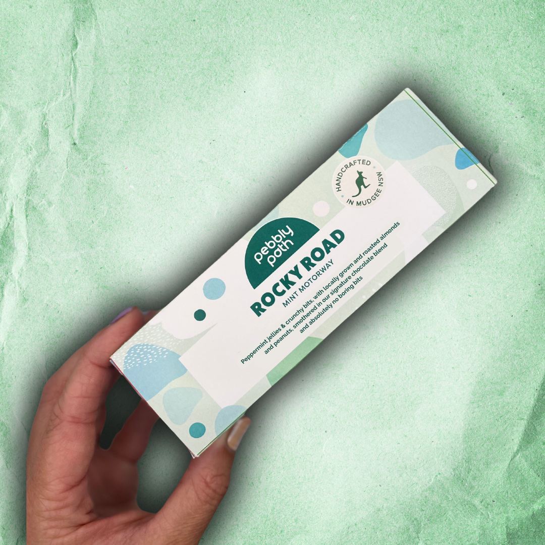 A hand holding the Mint Motorway rocky road box on a pale green background