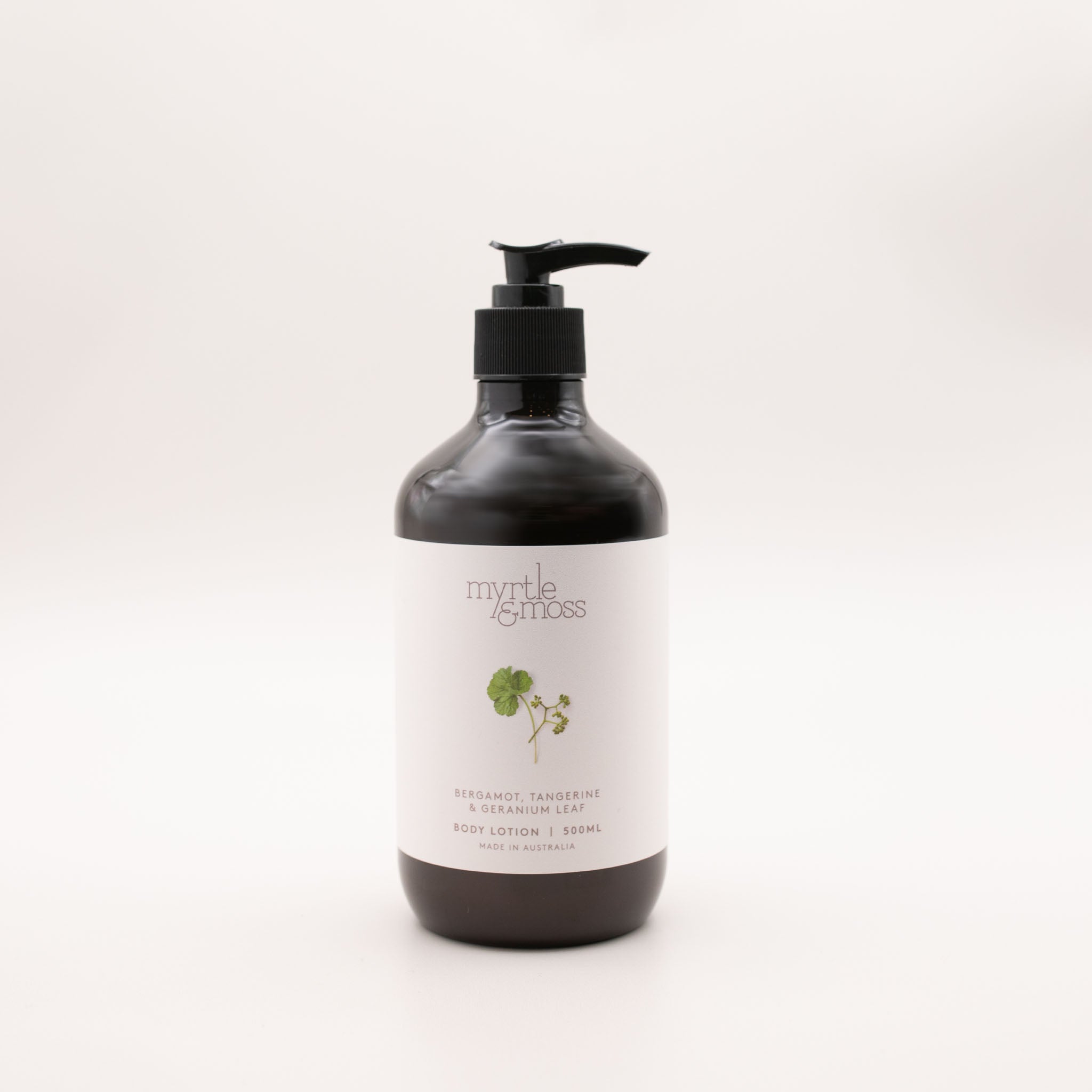 Myrtle & Moss Bergamot body lotion in a 500ml amber glass bottle with a black pump and a pale label showing a green geranium-leaf sprig.