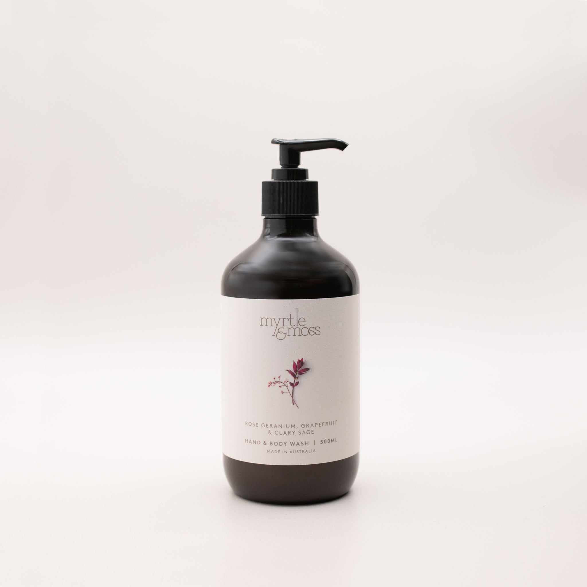 Myrtle & Moss Rose Geranium hand and body wash in a 500ml amber glass bottle with a black pump and a pale label showing a burgundy sprig.