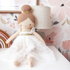 Lottie doll seated beside a lamp against pink floral wallpaper