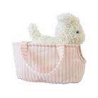 Marshmallow puppy plush peeking over the edge of its pink striped carrier