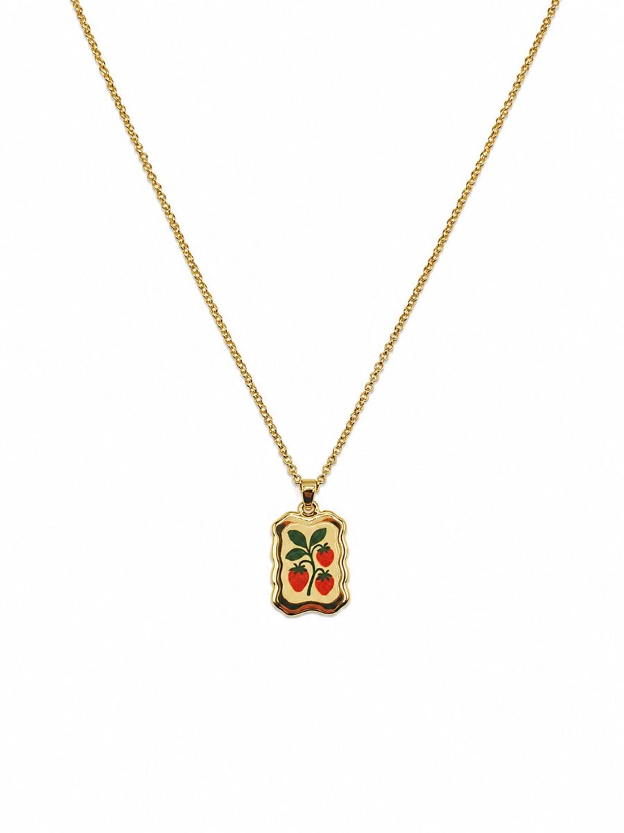 Gold-tone chain necklace with a wavy-edged rectangular pendant showing three red strawberries and green leaves on a cream background