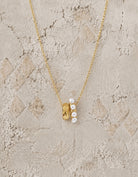 Fine gold chain necklace with a wide gold bead pendant set with a row of small white pearls