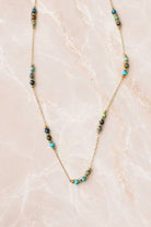 Fine gold chain necklace with small turquoise stone beads grouped in clusters along the chain