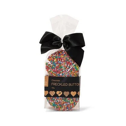 Clear cello bag of rainbow-sprinkled chocolate freckle buttons tied with a black satin bow, with a black Chocamama Freckled Button label