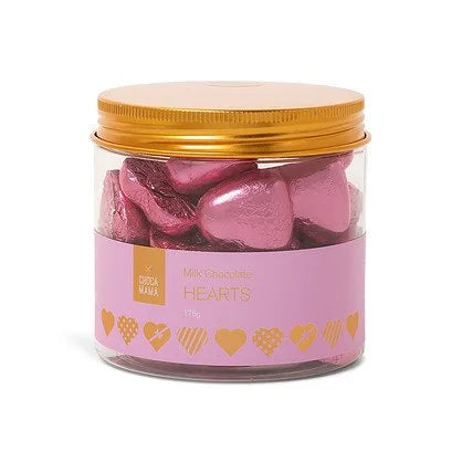 Clear tub of pink foil-wrapped milk chocolate hearts with a gold screw lid and a pink label edged in gold hearts