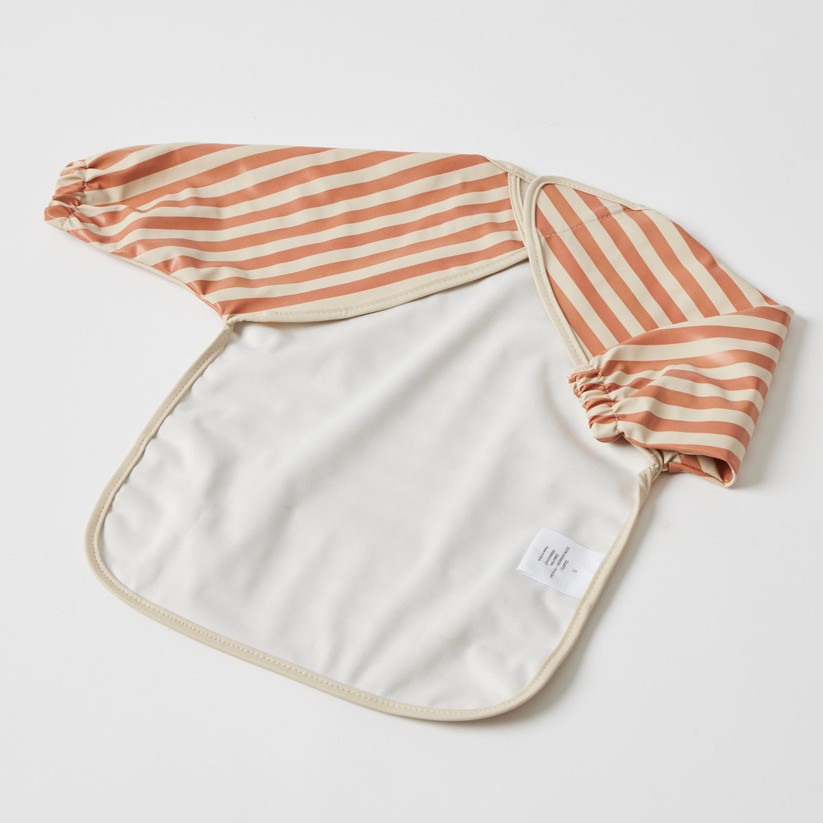 The smock turned over to show its open back and the plain cream inside of the front panel