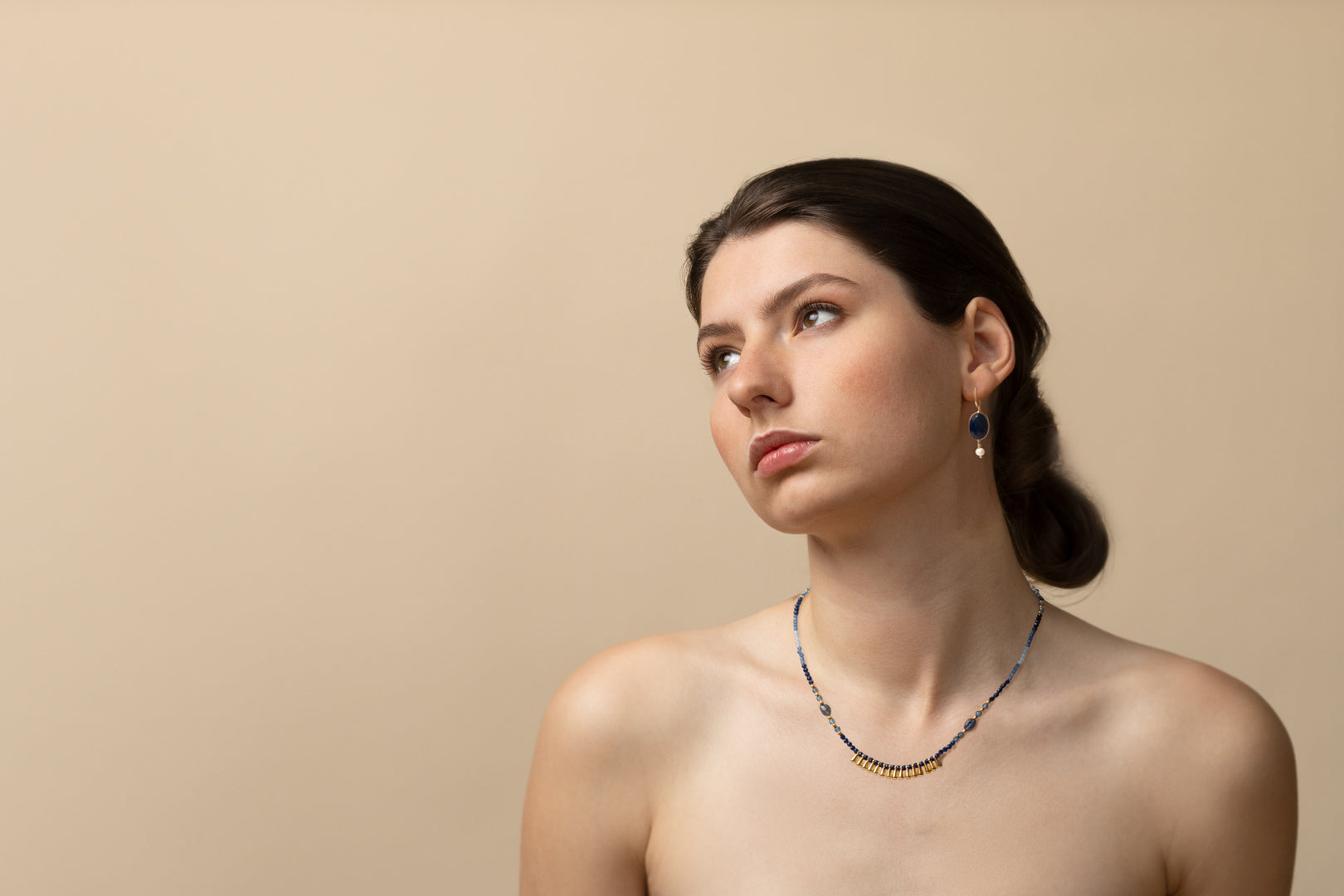 Model wearing delicate Euro Gold drop earrings and a fine beaded necklace