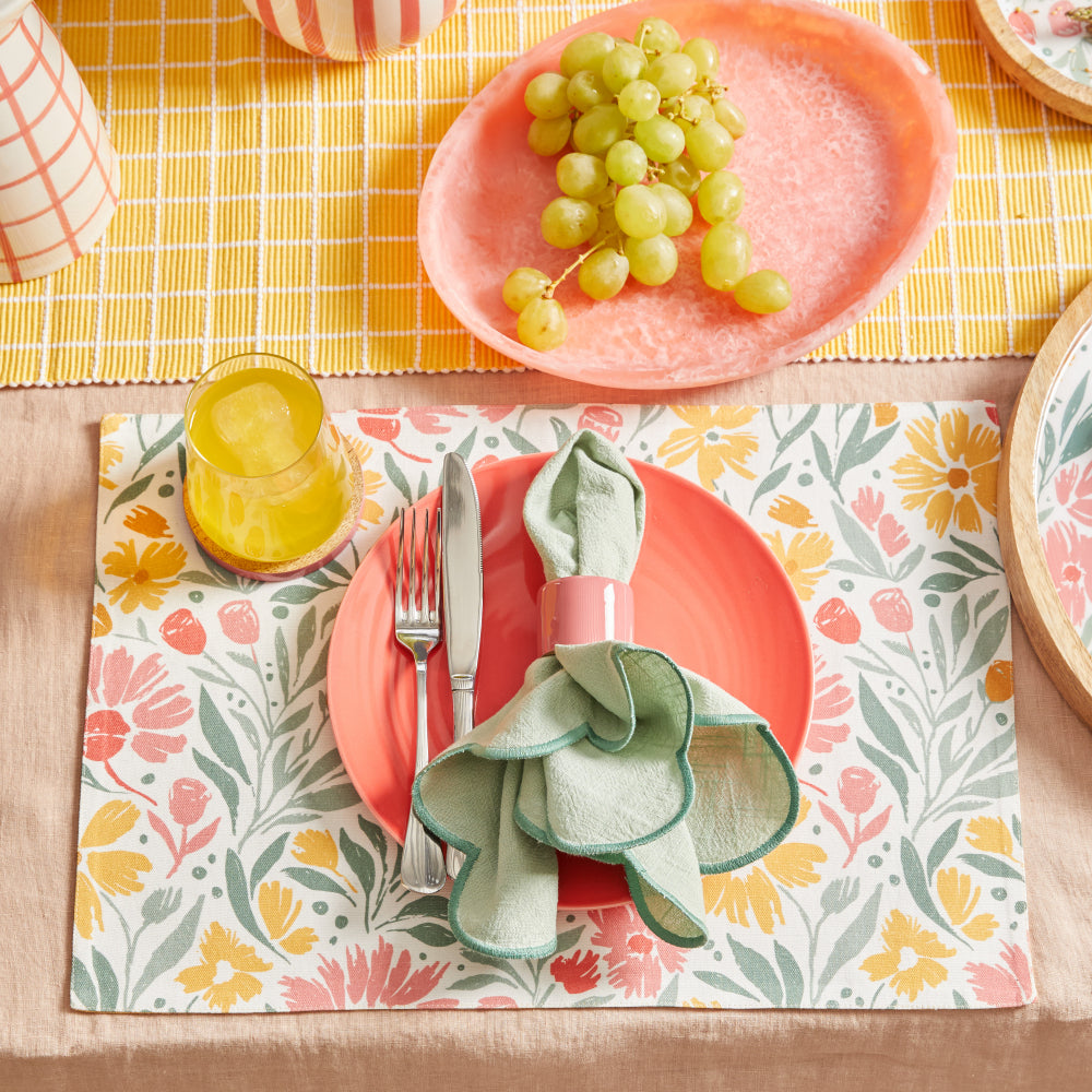 Bright table setting with a Nikkie coaster under a glass of juice beside a floral placemat