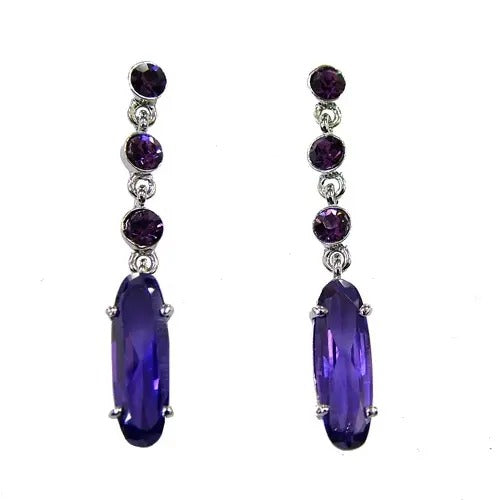 Pair of dark purple crystal drop earrings with three round stones above a long oval stone, silver tone, on white