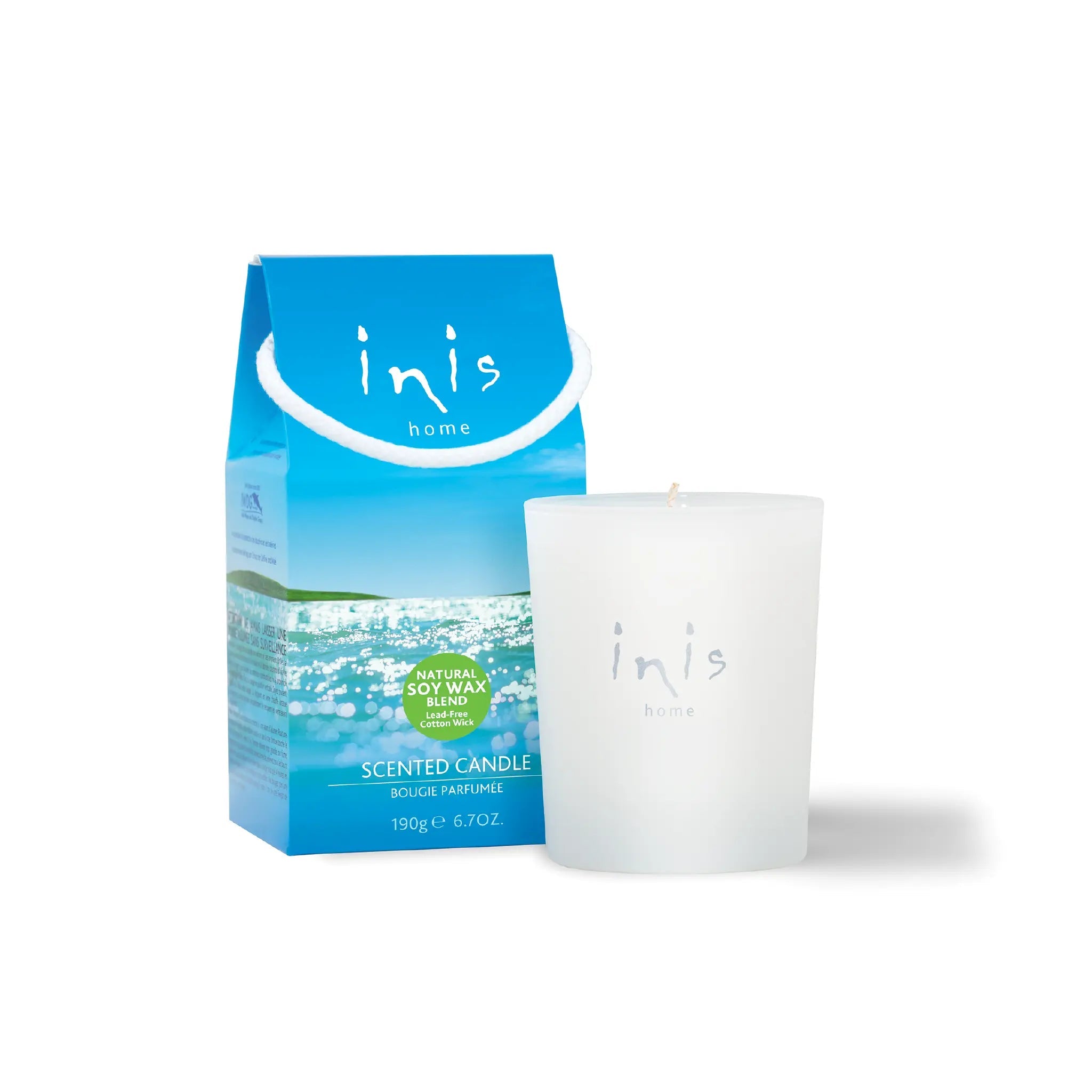 Inis Scented Candle in a frosted glass vessel beside its blue rope-handled gift carton