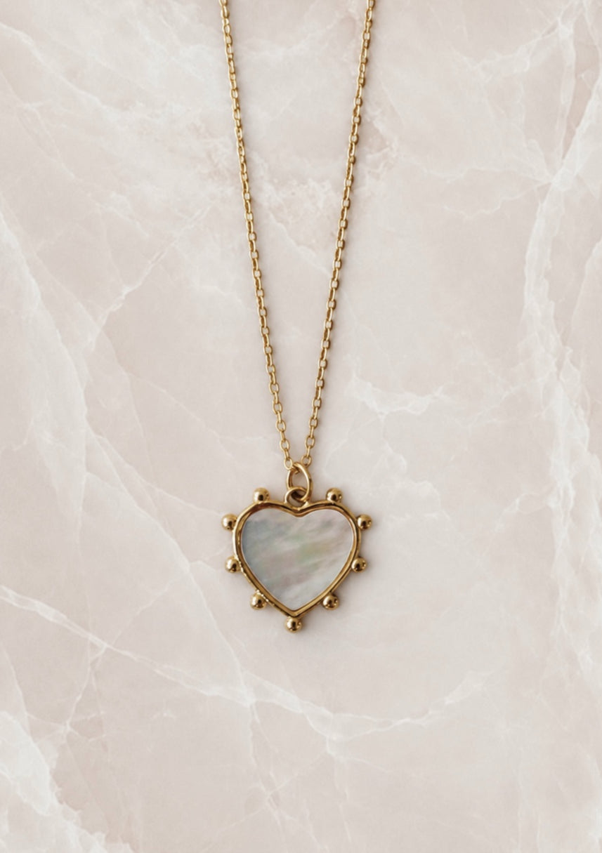 Gold chain necklace with a mother of pearl heart pendant edged in small gold beads