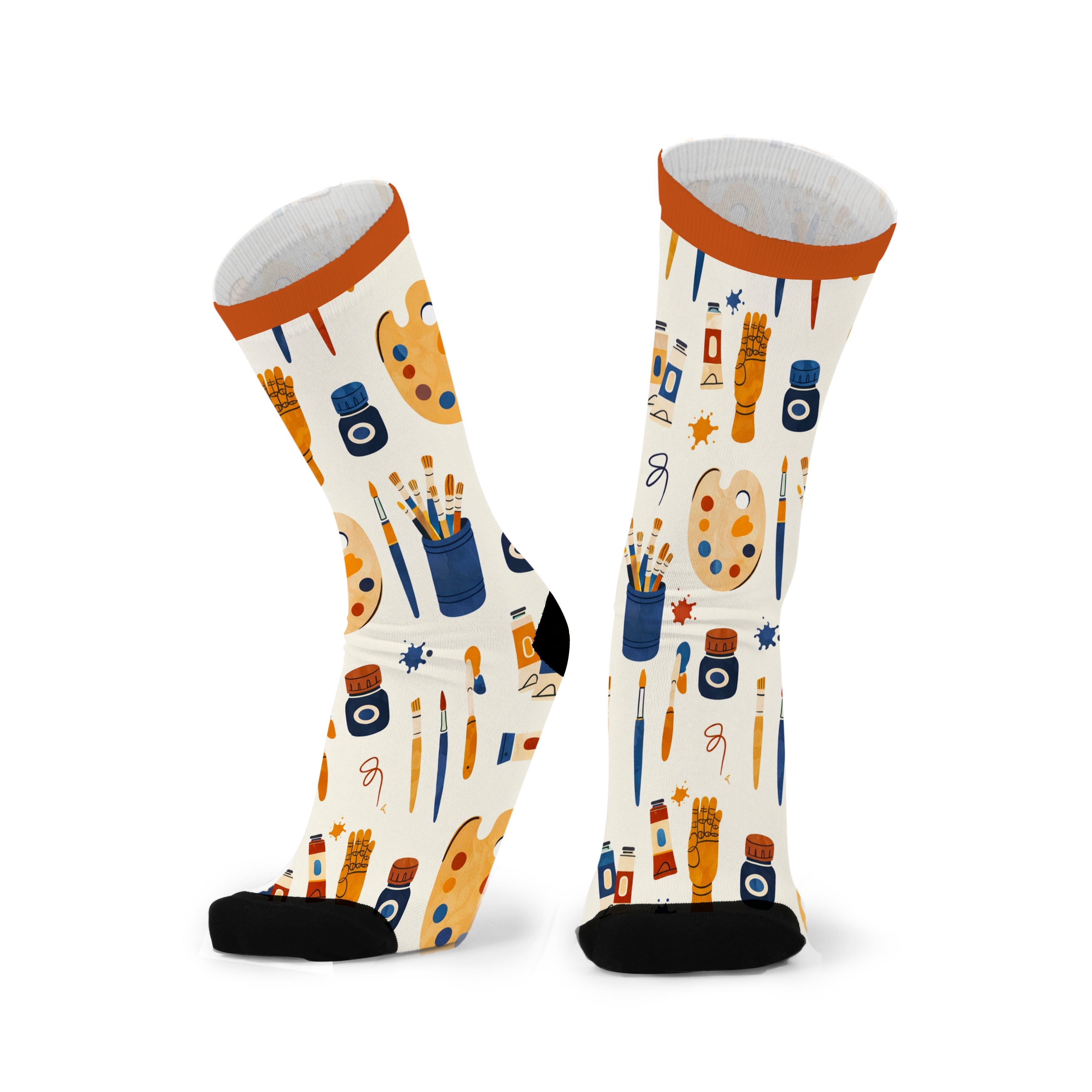 Pair of cream crew socks with a bright orange cuff and black toe, printed with paint palettes, brushes, tubes and ink bottles in ochre, navy and orange.