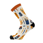 Side view of a single cream sock with an orange cuff and black toe, showing the painting and art supplies print wrapping around the foot.