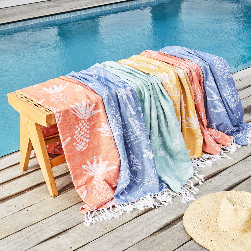 Colourful Turkish towels draped over a stool on a pool deck